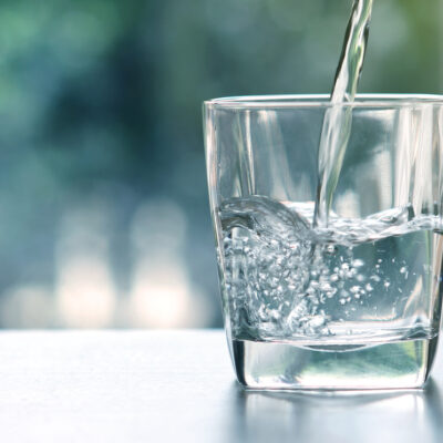 Close up pouring purified fresh drink water from the bottle on table in living room