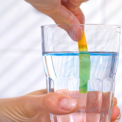 someone testing their water with a pH strip to see if they have alkaline water in the gulf coast area