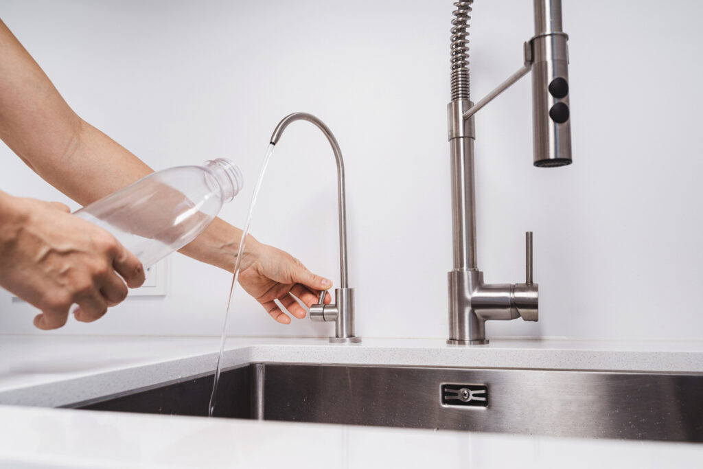 someone using an under sink RO filtration system