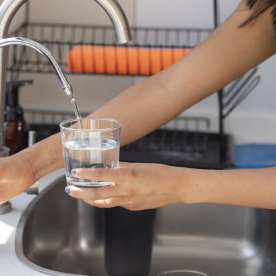 Lady pouring water from her under sink reverse osmosis water system