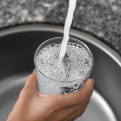 water pouring out of a faucet into a drinking glass